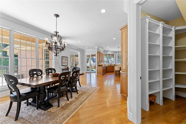 dining room with ornamental molding, light hardwood / wood-style floors, and an inviting chandelier