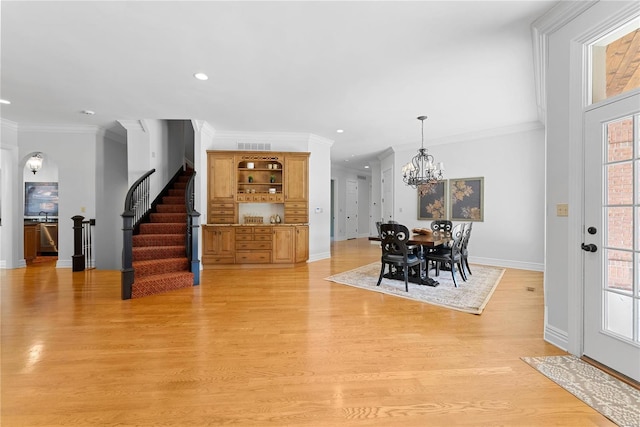 dining area featuring light wood-type flooring, ornamental molding, and a chandelier