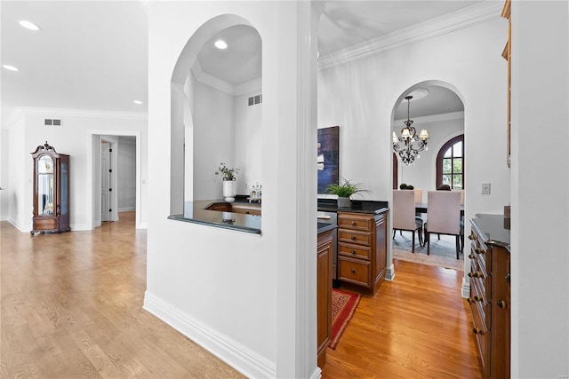 hallway featuring light hardwood / wood-style floors, ornamental molding, and a chandelier