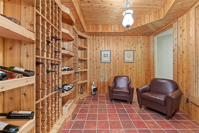 wine area with dark tile patterned floors, wooden ceiling, and wooden walls