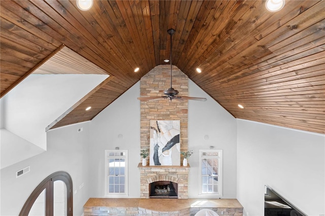 unfurnished living room with high vaulted ceiling, a stone fireplace, and wooden ceiling