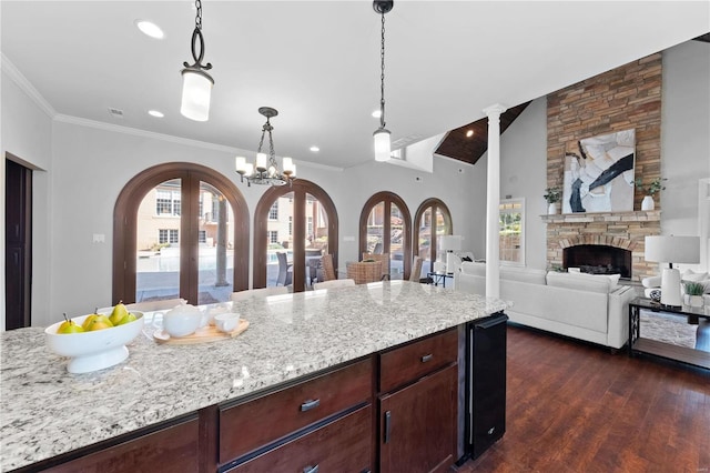 kitchen with a stone fireplace, a chandelier, pendant lighting, and a wealth of natural light