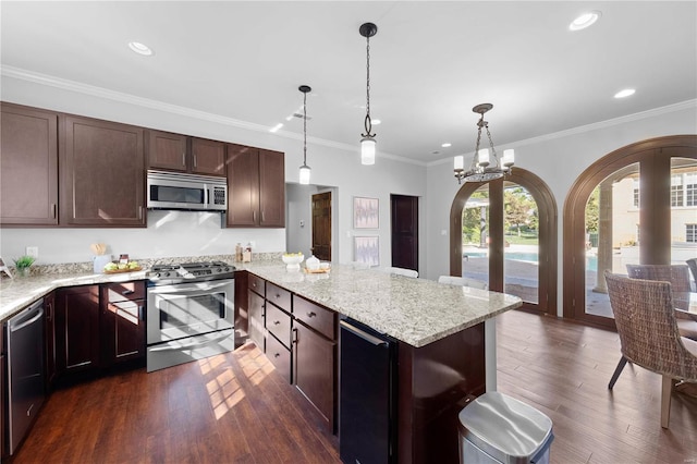 kitchen featuring pendant lighting, dark hardwood / wood-style floors, ornamental molding, and appliances with stainless steel finishes