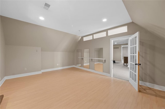 additional living space with french doors, light wood-type flooring, and lofted ceiling