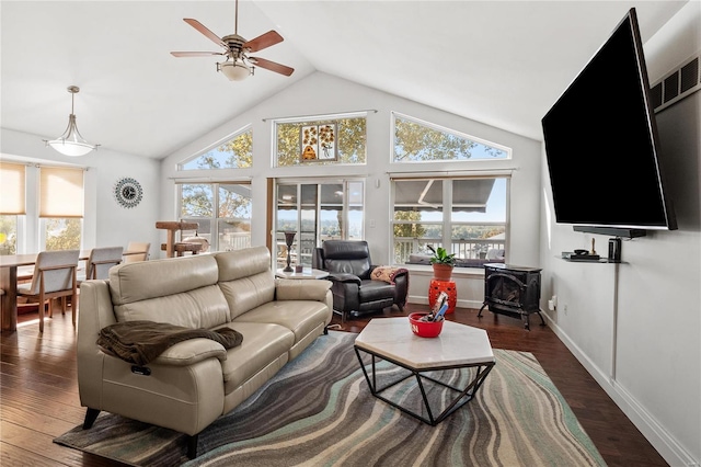 living room with vaulted ceiling, dark hardwood / wood-style floors, a wood stove, and ceiling fan