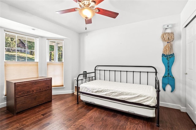 bedroom with ceiling fan, dark wood-type flooring, and a closet