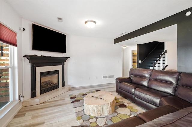 living room featuring light hardwood / wood-style flooring and a tiled fireplace