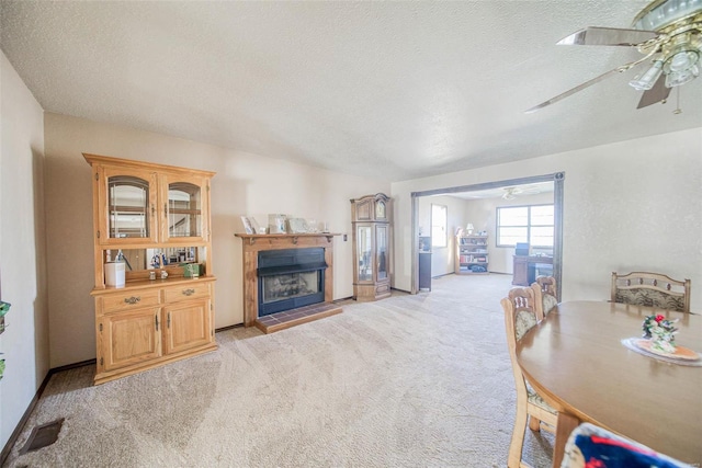 living room with light carpet, ceiling fan, and a textured ceiling