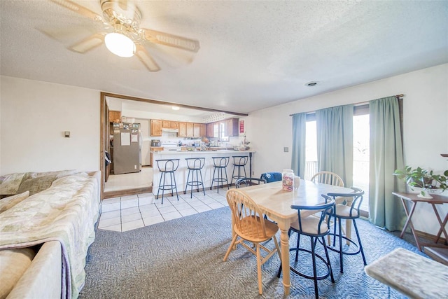 dining space featuring ceiling fan, light tile patterned floors, and a textured ceiling