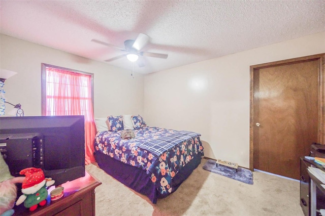 bedroom with ceiling fan, light colored carpet, and a textured ceiling