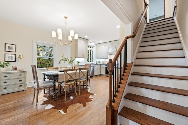 dining room with sink, light hardwood / wood-style flooring, and an inviting chandelier