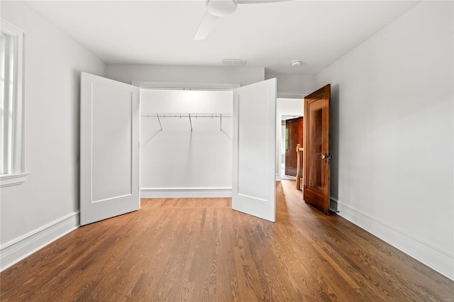 unfurnished bedroom featuring ceiling fan, wood-type flooring, and a closet