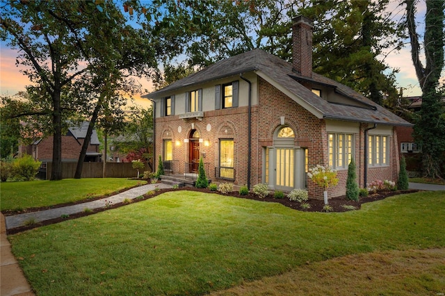 english style home featuring a yard