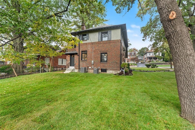 rear view of property with central AC unit and a yard