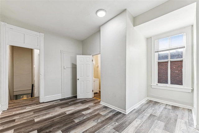 unfurnished bedroom with a closet, ensuite bathroom, and wood-type flooring