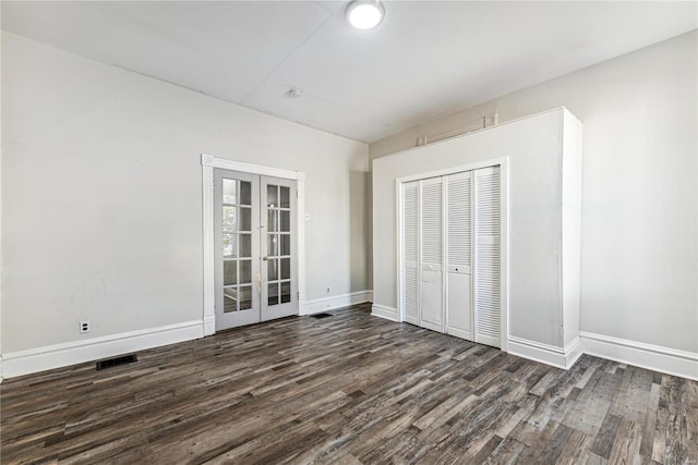 unfurnished bedroom with dark wood-type flooring, a closet, and french doors