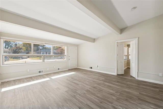 spare room featuring beamed ceiling and dark wood-type flooring