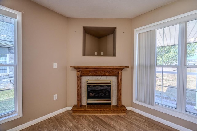 unfurnished living room with a wealth of natural light, a fireplace, and hardwood / wood-style flooring