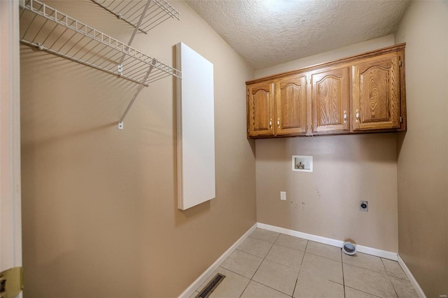 clothes washing area featuring cabinets, washer hookup, a textured ceiling, light tile patterned flooring, and electric dryer hookup