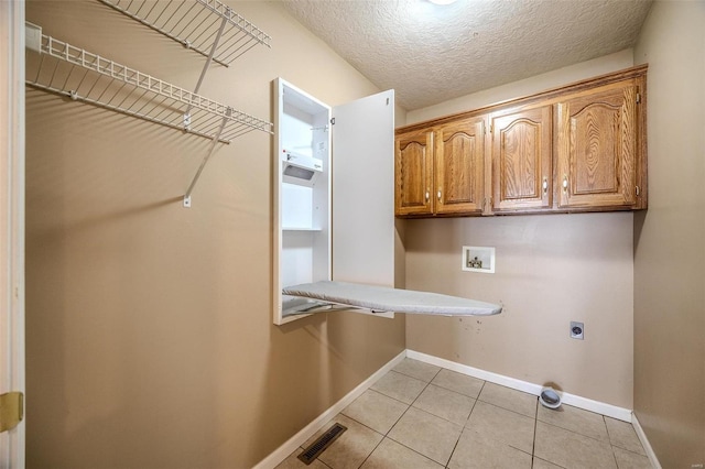 laundry room with cabinets, washer hookup, light tile patterned floors, a textured ceiling, and hookup for an electric dryer