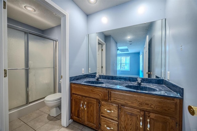 bathroom with vanity, toilet, a shower with shower door, and tile patterned flooring