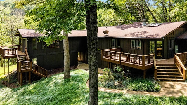 rear view of property featuring a wooden deck and a yard