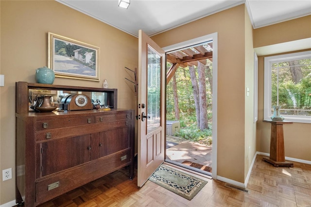 entryway with crown molding and light parquet flooring