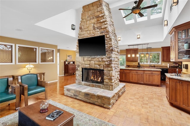 living room with ceiling fan, light parquet floors, high vaulted ceiling, and a stone fireplace