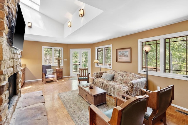 living room featuring french doors, vaulted ceiling, a stone fireplace, and light parquet flooring