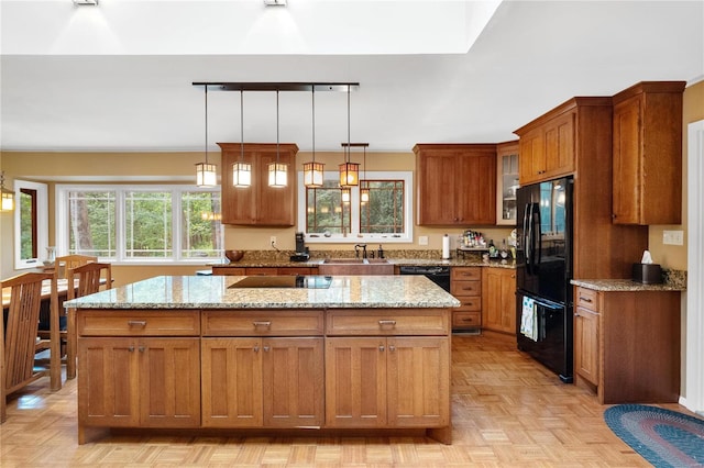 kitchen featuring light stone counters, black appliances, and a kitchen island