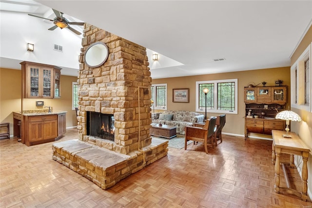 living room featuring a stone fireplace, ceiling fan, light parquet floors, and vaulted ceiling