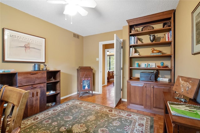 home office featuring a textured ceiling, light parquet flooring, and ceiling fan