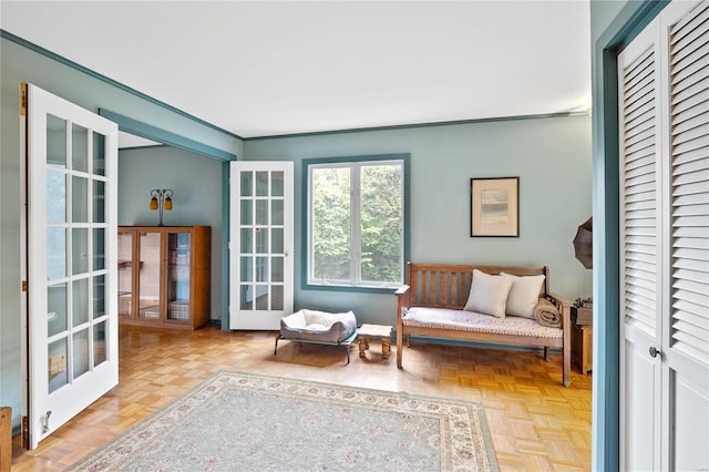 sitting room with french doors, ornamental molding, and light parquet floors