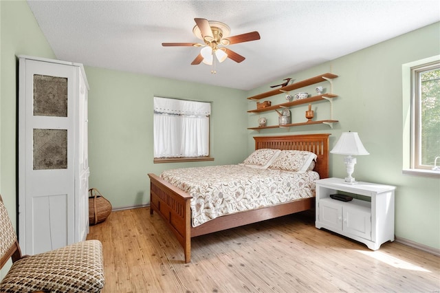 bedroom with a textured ceiling, light hardwood / wood-style floors, and ceiling fan