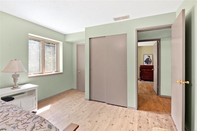 unfurnished bedroom featuring a closet, a textured ceiling, and light wood-type flooring