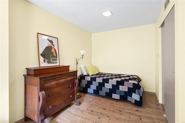 bedroom featuring light hardwood / wood-style floors, a closet, and a textured ceiling