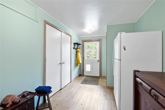 doorway with crown molding and light hardwood / wood-style flooring