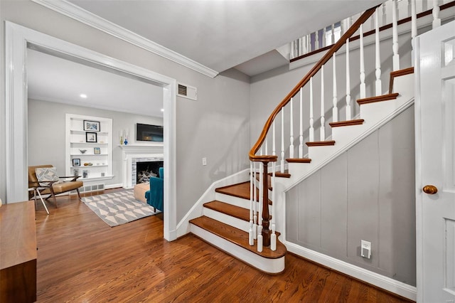 stairs featuring built in shelves, wood-type flooring, and ornamental molding