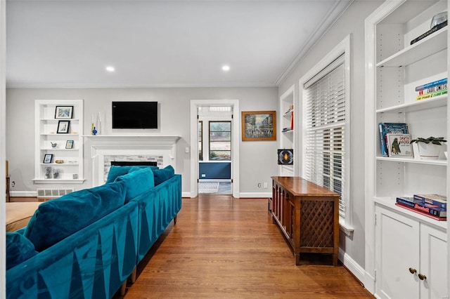 living room featuring hardwood / wood-style flooring, a stone fireplace, and ornamental molding