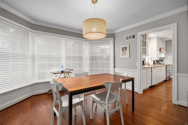 dining space featuring sink, crown molding, and dark wood-type flooring