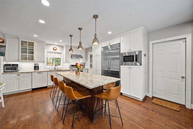 kitchen featuring built in appliances, white cabinets, and a kitchen island