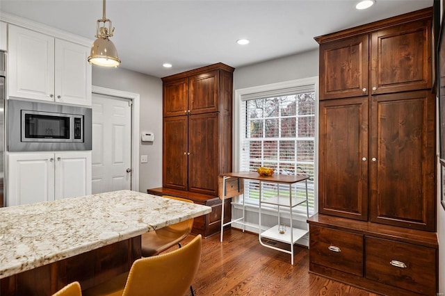 kitchen with pendant lighting, stainless steel microwave, plenty of natural light, and dark wood-type flooring