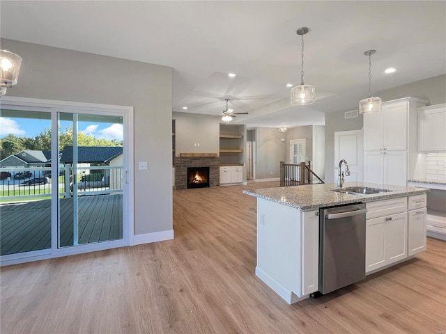 kitchen with white cabinets, a kitchen island with sink, light wood-type flooring, dishwasher, and sink