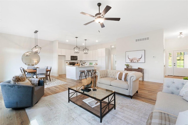 living room with sink, light wood-type flooring, and ceiling fan