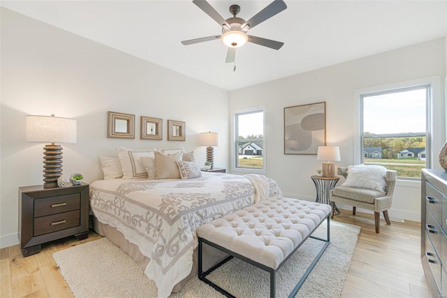 bedroom with ceiling fan, multiple windows, and light wood-type flooring