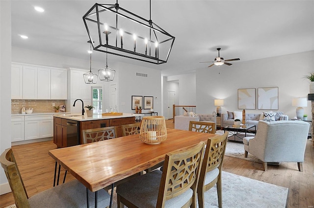 dining area featuring sink, ceiling fan with notable chandelier, and light hardwood / wood-style floors