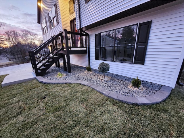 property exterior at dusk featuring a lawn