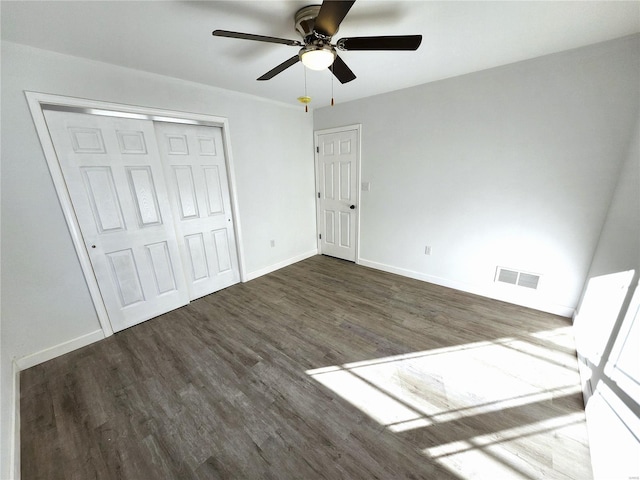 unfurnished bedroom with dark wood-type flooring, ceiling fan, and a closet