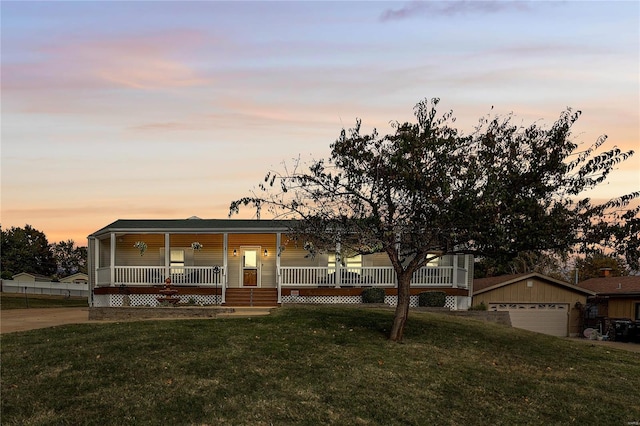 view of front of house with a lawn, an outdoor structure, covered porch, and a garage