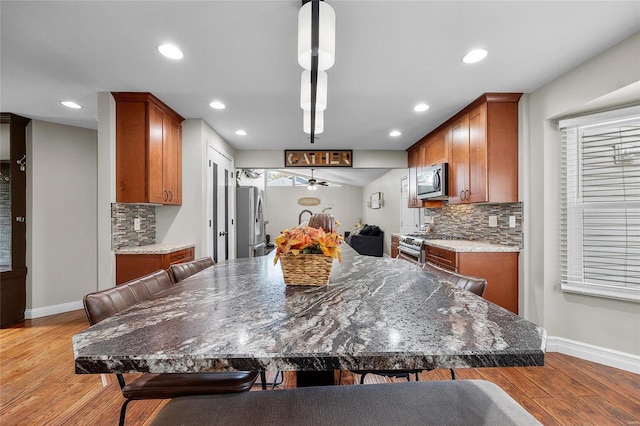 kitchen with ceiling fan, light wood-type flooring, decorative backsplash, and stainless steel appliances